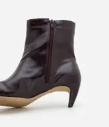 Bota de caña media Satinato, confeccionada en poliuretano con acabado brillante. Presenta diseño ajustado al tobillo, punta cuadrada y tacón fino de 6 cm. Incluye cierre lateral discreto.