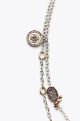 Pack de dos collares de diferente longitud con eslabones metálicos plateados. El primer collar presenta un colgante de corazón labrado con incrustaciones de piedra y cristal. El segundo collar incluye un colgante de medalla labrada con detalles en resina a color.
