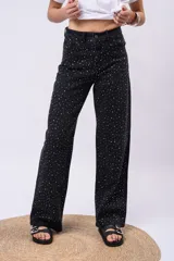 Pantalón wide leg de tiro alto confeccionado en denim negro, adornado con brillos de strass distribuidos por todo el frente.