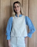 Chaleco de corte recto y largo a la cintura, confeccionado en denim con estampado de rayas verticales en tonos azul y blanco. Presenta cuello redondo y costuras visibles que definen su estructura.