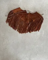 Pechera de cuero vacuno en color negro, diseñada con flecos largos y cierre frontal mediante lazo. Es un accesorio versátil tipo cuello para complementar prendas básicas.