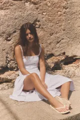 Vestido midi de popelín color blanco, con escote cuadrado y tirantes anchos. Presenta un diseño con godets que aportan volumen a la falda y cierre lateral con cremallera oculta.