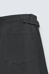 Pantalón de corte relajado confeccionado en tejido de algodón. Presenta cintura con trabillas laterales ajustables, bolsillos frontales y traseros, y un diseño distintivo de costuras laterales giradas que recorren la pernera.
