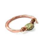 Pulsera rígida de cobre con cuentas de piedra natural en tonos verdes y marrones.