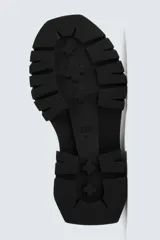 Bota tipo Chelsea de caña media, confeccionada en material sintético liso color negro. Presenta paneles elásticos laterales, tirador trasero y una suela robusta con plataforma track de gran volumen.