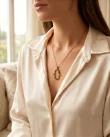 Collar de acero con baño de oro, compuesto por una cadena fina y un dije en forma de mano de Hamsa con relieve y engaste de circonias multicolor.