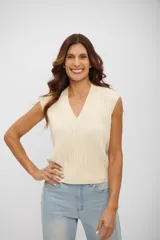 Chaleco de punto color crema con cuello en V y diseño de trenzas verticales. Presenta terminaciones acanaladas en el cuello, sisas y ruedo.