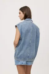 Chaleco de jean negro de calce relajado, con cuello camisero, cierre frontal con botones metálicos y bolsillos delanteros con solapa.