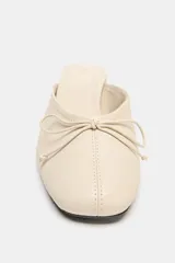 Zapatos de tacón tipo bailarina destalonada en piel color beige, con detalle de lazo en la parte delantera, tacón en bloque y punta redonda.