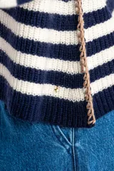 Sweater de lana con rayas horizontales en tonos rojo, rosa, beige y marrón. Presenta costuras decorativas en los laterales y puños en color violeta.