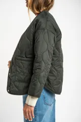 Campera acolchada color verde militar, con cuello redondo y cierre frontal de broches a presión. Presenta un patrón de costuras onduladas.