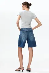 Bermudas de cinco bolsillos en denim de algodón rígido, con talle alto, cierre de cremallera y botón.