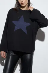 Sweater negro de tejido de punto con una estrella azul con brillos en el centro.
