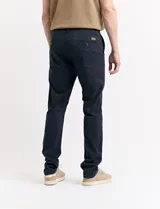 Pantalón de vestir marrón, de corte recto, con bolsillos laterales y traseros. Se ajusta a la cintura con cinturón de cuero marrón.