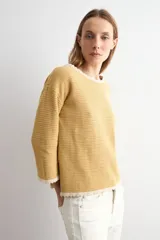 Sweater de punto negro con escote bote, mangas largas y detalles de terminación en ondas de color blanco en el cuello, los puños y el ruedo.
