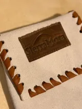 Funda para celular de gamuza azul marino con correa de cuero marrón y aplique de cuero marrón con logo de la marca.