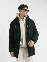 Campera puffer negra con capucha, cierre frontal y bolsillo con cierre en el pecho. Diseño acolchado de corte largo.