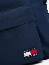 Mochila de diseño redondeado color azul marino, con asa superior, correas ajustables y acolchadas. Presenta un compartimento principal con cierre, bolsillo exterior con cremallera y parche con el logo de Tommy Jeans en la parte delantera.