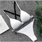 Conjunto de bikini United modelo H50408, color blanco con detalles de tiras plateadas con brillo. El corpiño es de diseño triangular y la bombacha es de tipo tanga.