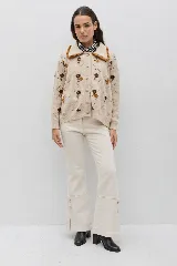 Saco de punto color bordó con bordados artesanales de flores en tonos rosados. Presenta un cuello con detalle de volados en color crema y cierre frontal con botones. De silueta amplia y cómoda.