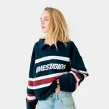 Buzo tipo polo de manga larga con diseño a rayas horizontales en blanco y bordó sobre base azul marino. Presenta el nombre de la marca estampado en el frente y cuello camisero.