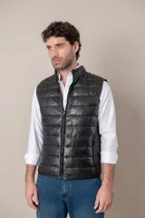 Chaleco de cuero negro con cierre frontal y cuello mao. Diseño acolchado horizontal.