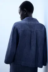 Camisa de lino azul, con cuello solapa, escote en V y mangas por debajo del codo.