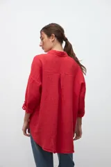 Camisa de lino color rojo, de corte oversize, con cuello clásico, cierre frontal de botones y bolsillo en el pecho.