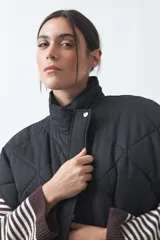 Chaleco acolchado de nylon con diseño capitoneado, cuello alto y cierre frontal con botones a presión. Presenta un calce amplio y versátil.