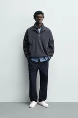 Sobrecamisa de corte regular confeccionada en mezcla de algodón y lyocell, con cuello alto y cierre frontal de cremallera. Presenta mangas largas con puños elásticos, bolsillos laterales de vivo y bajo ajustable con elástico en los laterales.