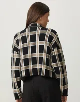 Chaqueta negra de tejido de punto con diseño a cuadros en tonos beige y blanco, cuello tipo blazer y bolsillos frontales.