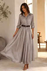 Vestido largo de seda gris con diseño camisero, escote en V con solapa, mangas 3/4 y falda amplia con vuelo. Incluye un cinturón trenzado marrón oscuro con hebilla metálica redonda.