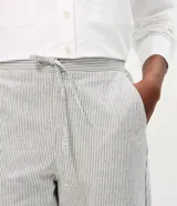 Pantalón de corte carrot con cintura alta, confeccionado en sarga de algodón con estampado de rayas verticales. Presenta un diseño holgado en la cadera que se estrecha hacia el tobillo, con bolsillos laterales y cierre frontal.