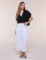 Blusa crop cruzada Allie Rose de tela liviana negra con estampado de lunares blancos, escote en V y cuello camisero.