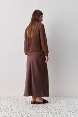Falda midi color negro al bies, confeccionada en tela de textura suave y caída fluida, de diseño minimalista y silueta recta.