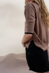 Buzo de tejido de punto en color gris claro, con diseño holgado, mangas tres cuartos con puños acanalados y detalle de línea en color contrastante en el ruedo.
