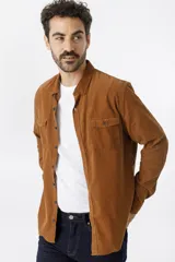 Camisa de pana color marrón, con cuello clásico, cierre frontal de botones y dos bolsillos con solapa en el pecho.