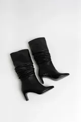 Botas de caña alta de cuero negro con efecto arrugado, punta fina y tacón fino.