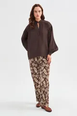 Blusa de lyocell color marrón, con diseño holgado, escote en V con cordón para atar y mangas largas abullonadas con puños ajustados.
