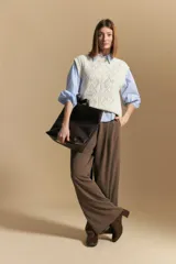 Chaleco tejido color crema con diseño de rombos calados, cuello redondo y sisas.