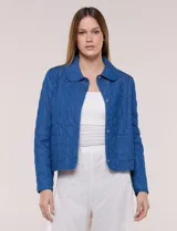 Chaqueta azul de algodón con diseño acolchado y bordado de flores, cuello redondo y cierre frontal con botones a presión metálicos. Incluye bolsillos delanteros y forro interno a tono.