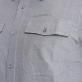 Camisa de manga corta Merrell, color gris, con cuello clásico y cierre frontal de botones. Presenta dos bolsillos frontales con solapa y logo de la marca estampado en el pecho.