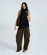 Pantalón sastre de corte barrel, con diseño de piernas anchas y volumen estructurado en los laterales. Presenta pliegues frontales, cintura con elástico en la parte posterior y acabado refinado.