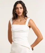 Blusa alargada de bengalina color blanco, con tirantes anchos, escote cuadrado, fruncido lateral y dobladillo asimétrico.