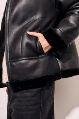 Campera gamulan negra con cuello, puños y ruedo de piel sintética.