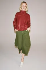 Jeans capri de tiro medio y corte balloon leg en color verde militar. Presenta trabillas en la cintura, bolsillos laterales y bolsillos de plastrón tipo cargo en las piernas. Cuenta con cierre frontal con cremallera y botón metálico.