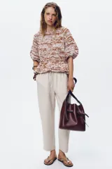 Pantalón tobillero color beige, con cintura elástica ajustable con cordones, bolsillos delanteros y falsos bolsillos con solapa en la espalda.