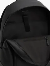 Mochila Tommy Hilfiger de color negro, confeccionada en poliuretano con paneles de texturas mixtas y diseño curvo. Cuenta con un compartimento principal con cremallera de doble cierre, funda interior para portátil, bolsillo interior con cremallera y un bolsillo exterior frontal con cierre y detalles en rojo y azul marino. Incorpora asa superior, correas ajustables y acolchadas, respaldo con panel de malla acolchado y logo metálico de la marca en la parte delantera.