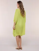 Vestido playero tipo túnica de corte holgado color rosado, confeccionado en tejido semi transparente con textura sutilmente arrugada. Cuenta con escote en V pronunciado, mangas estilo kimono de caída fluida y aberturas laterales en el ruedo irregular.