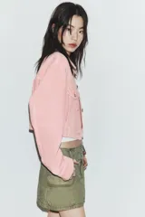 Cazadora de denim en color rosado, con cuello solapa, manga larga y cierre frontal con botones metálicos. Presenta bolsillos con solapa y botón en el pecho, además de trabillas en la cintura.